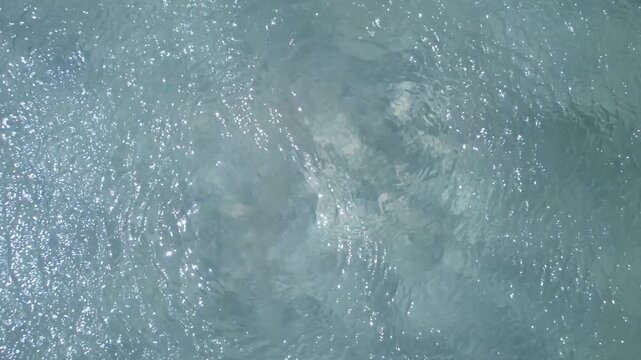 Moving water surface with light reflections and natural texture from above