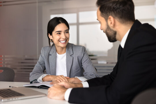 Smiling businesswoman talking with client or colleague in office, engaged in professional communication during consultation or teamwork meeting, discussing project detail, strategy, business solutions
