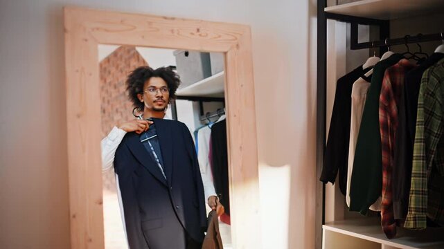 African american man holding suit jacket mirror. Fitting room menswear choice.
