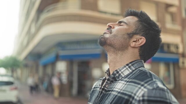 Man tilts head back with closed eyes showing neck and beard on a street corner storefront; quiet contemplation.