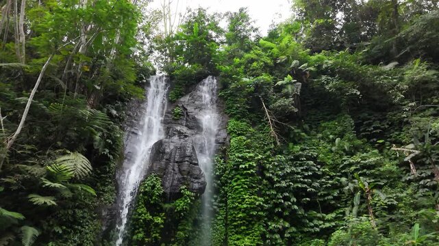 Drone flyin in circulair motion fliming the top of a double waterfall in the forest in 4k