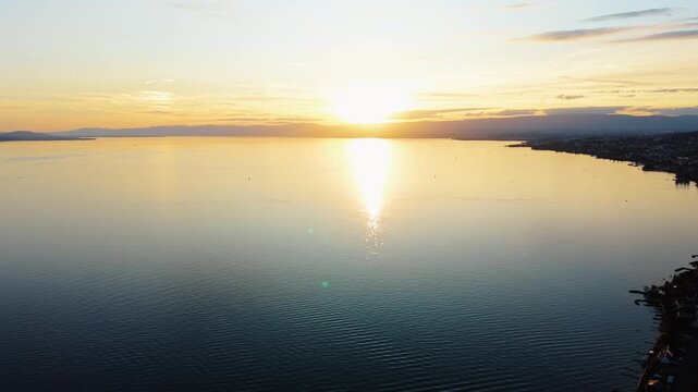 Drone flies backward over Lake Geneva near Cully, Switzerland at sunset