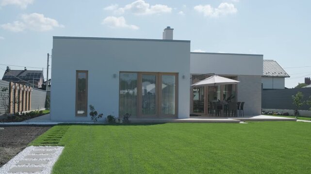 Modern single-story house with a flat roof and white facade.