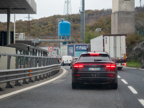 Traffic queuing at a motorway toll plaza, featuring an Audi SQ8 navigating the slow moving line alongside trucks and vans, symbolizing busy routes and the journey ahead
