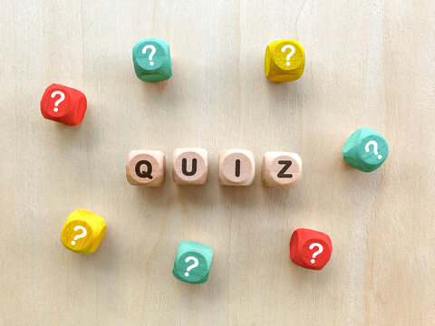 Wooden blocks spelling QUIZ surrounded by colorful question marks.