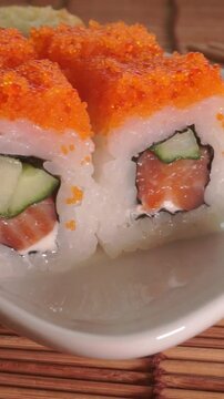 Macro shot focusing on the delicious texture of Philadelphia sushi rolls with orange flying fish caviar and fresh cucumber filling.