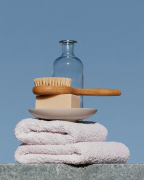 Balanced stack of bathroom accessories with a soft towel, wooden brush, and glass bottle for spa and home brand campaigns, copy space