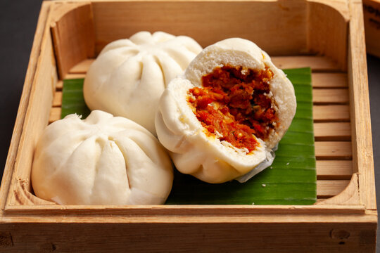 Steamed buns known as bao zi or bakpao served on banana leaf and wooden box