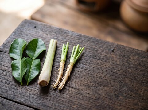 Kaffir lime leaves and lemongrass stalks on wooden table