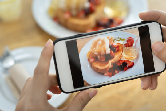 Traveler takes a photo of the food on the table with a smartphone to post on a website. Online food delivery, ordering service, influencer, review, social media, share, marketing, interest