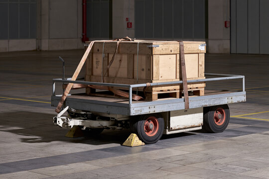 Loaded flatbed trolley stopped hard against a wheel chock in a warehouse bay