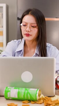 Asian Woman Working on Laptop and Eating Fried Chicken at Home