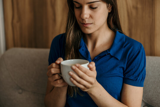 Woman holding coffee cup relaxing indoors with hot beverage