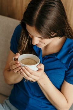 Woman enjoying morning coffee smelling warm aroma at home