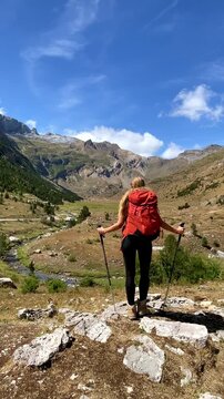 woman hiker with red backpack standing on mountain trail looking at vast valley view- Adventure, travel, freedom concept
