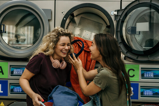 Young women having fun doing laundry at laundromat