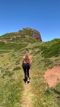 woman walking along scenic coastal trail outdoors in nature on sunny day- Active lifestyle, freedom, sport concept