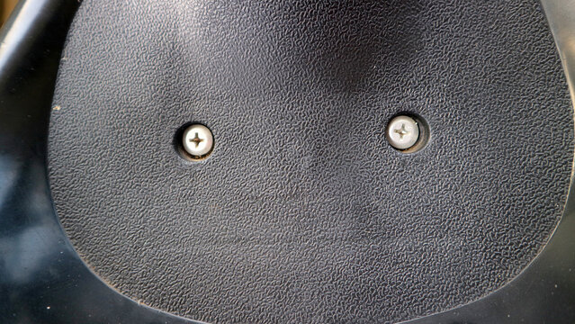 Detailed close up view of two cross head screws on textured black plastic surface