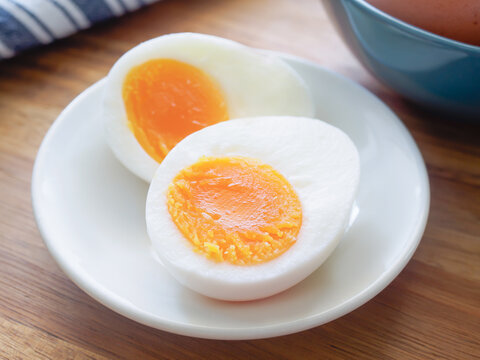 Soft boiled egg cut in half on a white plate on a wooden table
