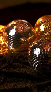 Silver and gold disco balls on black velvet with warm lights