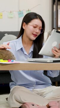 Asian Woman Working on Tablet While Petting Rabbit at Home