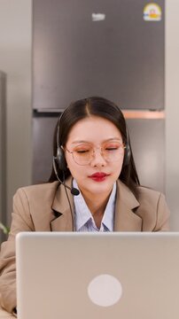 Asian Customer Service Representative Working on Laptop Wearing Headset at Home