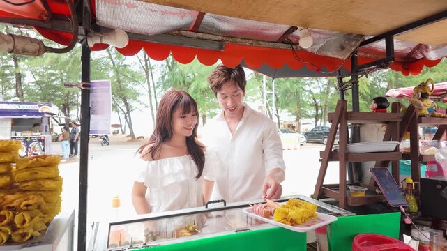 Young Asian Couple Choosing Street Food at Beach Cart