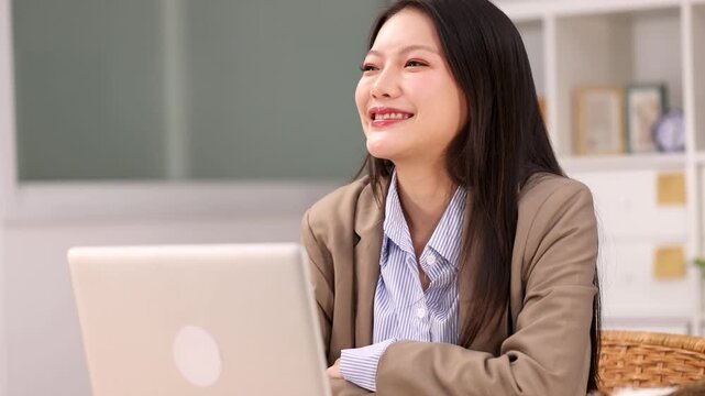 Asian Businesswoman Smiling While Working on Laptop in Office