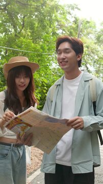 Young Asian Couple Reading Paper Map While Exploring Outdoors