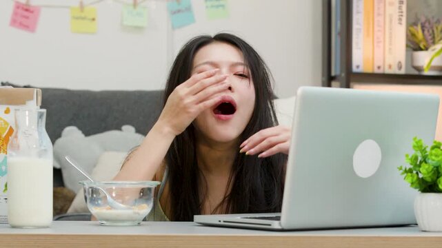 Tired Asian Woman Working from Home at Laptop and Yawning