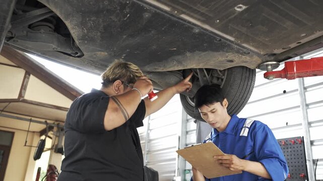 Mechanics inspecting underside of a car in garage