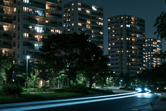 都会の夜空に輝くマンションと道路を走る車の光の軌跡