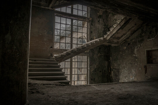Abandoned sanatorium in Tskaltubo: old classical stairway and stained-glass window inside resort spa building, Georgia, revealing faded architectural grandeur.

