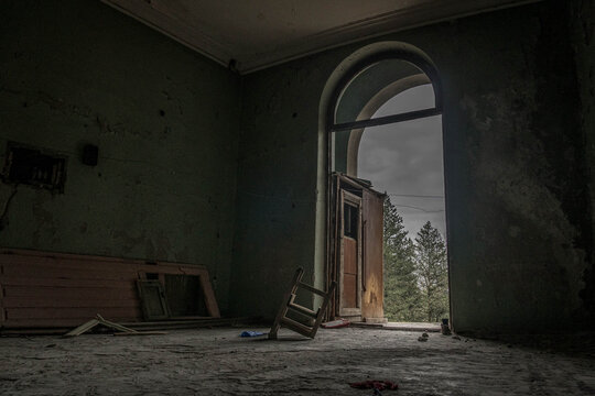 Interior of an abandoned sanatorium in Tskaltubo, Georgia, with a lone chair surrounded by forgotten belongings in a silent, empty room.
