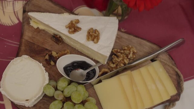 Cheese platter with grapes, walnuts, and jam on rustic board at festive table