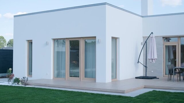 Modern single-story house with a flat roof and white facade.