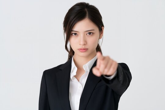 真剣な表情で指差しする日本人女性が注意喚起を促す