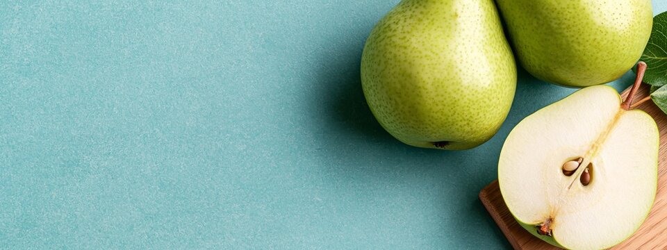 Fresh green pears rest on a soft teal surface