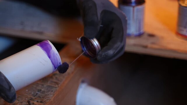 Close up view of Plumber applying purple primer to a PVC pipe fitting during residential plumbing installation.