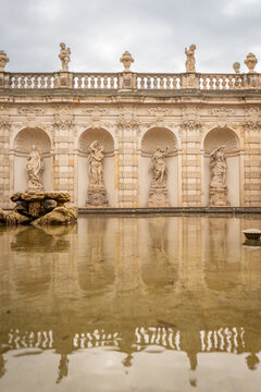 Dresden Zwinger architecture mirrored in a reflecting pool, with visitors admiring the ornate Baroque facade and sculptural details of the historic complex.