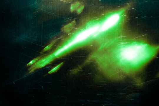 Retro film overlay effect with scratch dust and light leaks, bokeh, retro grain noisy film distressed texture light leak flare on black background. Grunge design. Wallpaper. Green speckled shine blur