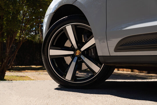 Grey Porsche Macan SUV front wheel close up detail parked on sunny paved driveway outdoors