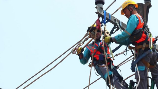 Electrical Workers in Full PPE Installing a Hoist on a Three-Phase Overhead Power Line