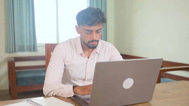 Serious young male professional working attentively on a laptop at home, focused on a task in a modern residential workspace. Smooth cinematic camera slider shot suitable for remote work, business, pr