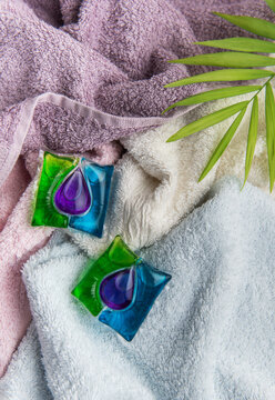 Laundry detergent pods on colorful clean towels with leaf