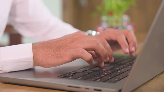Close-up side view of a young professional typing on a laptop keyboard while working at home. Detailed hands-on computer work suitable for remote work, business, technology, online work, productivity,