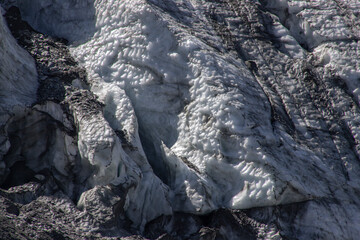 Glacier ice texture featuring white snow and dark rocks © Cavan