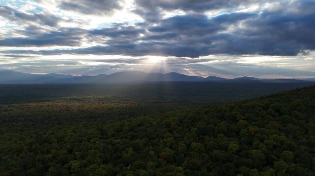 Sun rays shine over a vast forest and mountains, Maine.