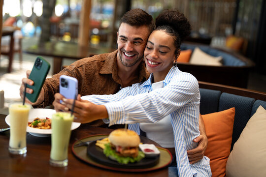Multiethnic couple enjoying a joyful dining experience by the beach. Great food, perfect summer vibe