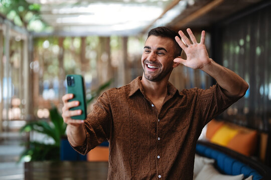 Smiling businessman using smartphone for communication in a modern cafe interior